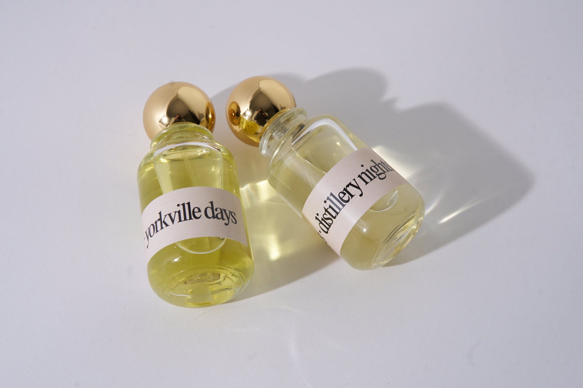Two small glass bottles with gold caps and labels on a white background